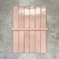 Nomad Rose bullnose pencil border ceramic tiles in a 3 × 20cm format, shown with matching brick tiles to highlight the soft pink colour, gloss finish and rounded edge detail.