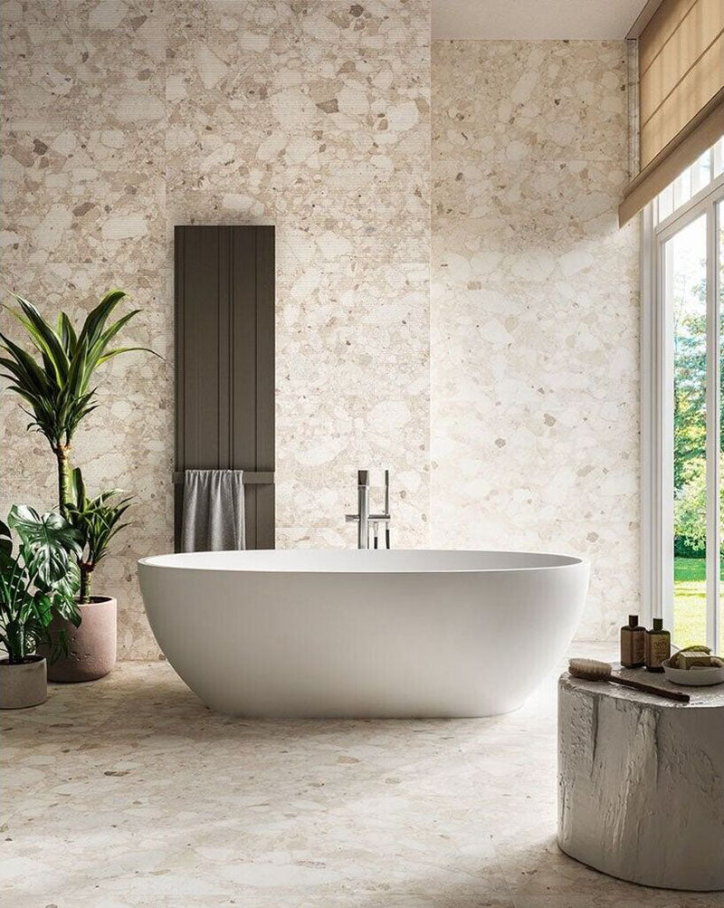 Luxury bathroom featuring Venice Ivory matt terrazzo effect porcelain tiles in a 60 x 120cm format across the walls and floor, creating a bright, seamless space with a freestanding bath and natural stone-inspired finish.