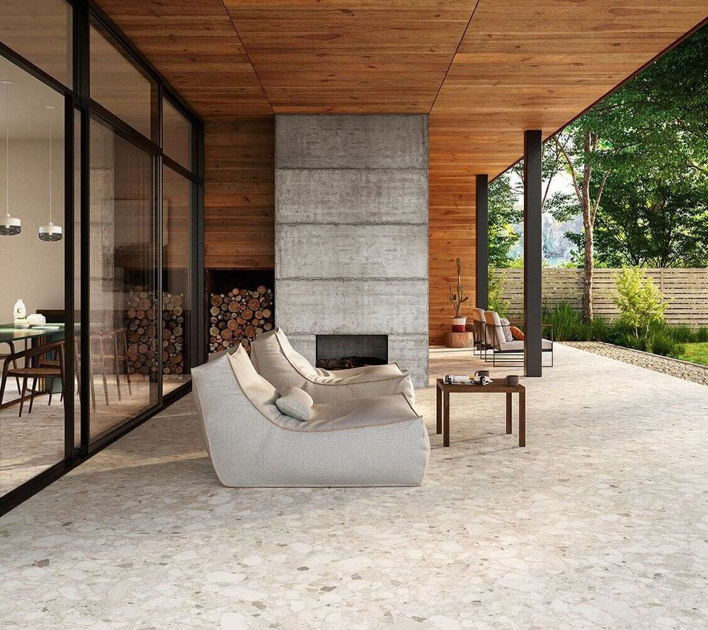 Covered outdoor patio featuring Venice Ivory matt terrazzo effect porcelain tiles in a 60 x 120cm format, creating a seamless indoor-outdoor look with soft ivory tones, contemporary furnishings and a modern fireplace.