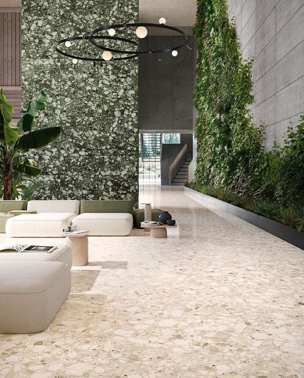 Spacious contemporary interior featuring Venice Ivory matt terrazzo effect porcelain tiles in a 60 x 120cm format, paired with a striking green terrazzo feature wall, indoor planting and modern minimalist furnishings.