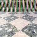 Venice Ivory and Venice Emerald matt terrazzo effect porcelain tiles laid in a striking chequerboard pattern, complemented by colourful gloss brick wall tiles for a bold, contemporary patio design.