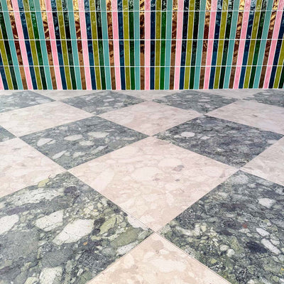 Venice Ivory and Venice Emerald matt terrazzo effect porcelain tiles laid in a striking chequerboard pattern, complemented by colourful gloss brick wall tiles for a bold, contemporary patio design.