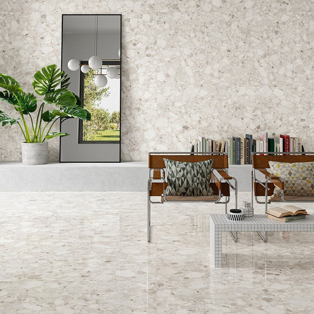 Contemporary living space featuring Venice Ivory polished terrazzo effect porcelain wall and floor tiles, showcasing soft ivory tones with natural stone chips, paired with modern furniture and greenery for a bright, elegant interior.