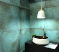 Contemporary bathroom featuring Verde Copper Oxide 60cm x 60cm metallic effect wall tiles, styled with a black vanity, vessel basin, pendant lighting and rich blue-green tones for a modern industrial-inspired interior.