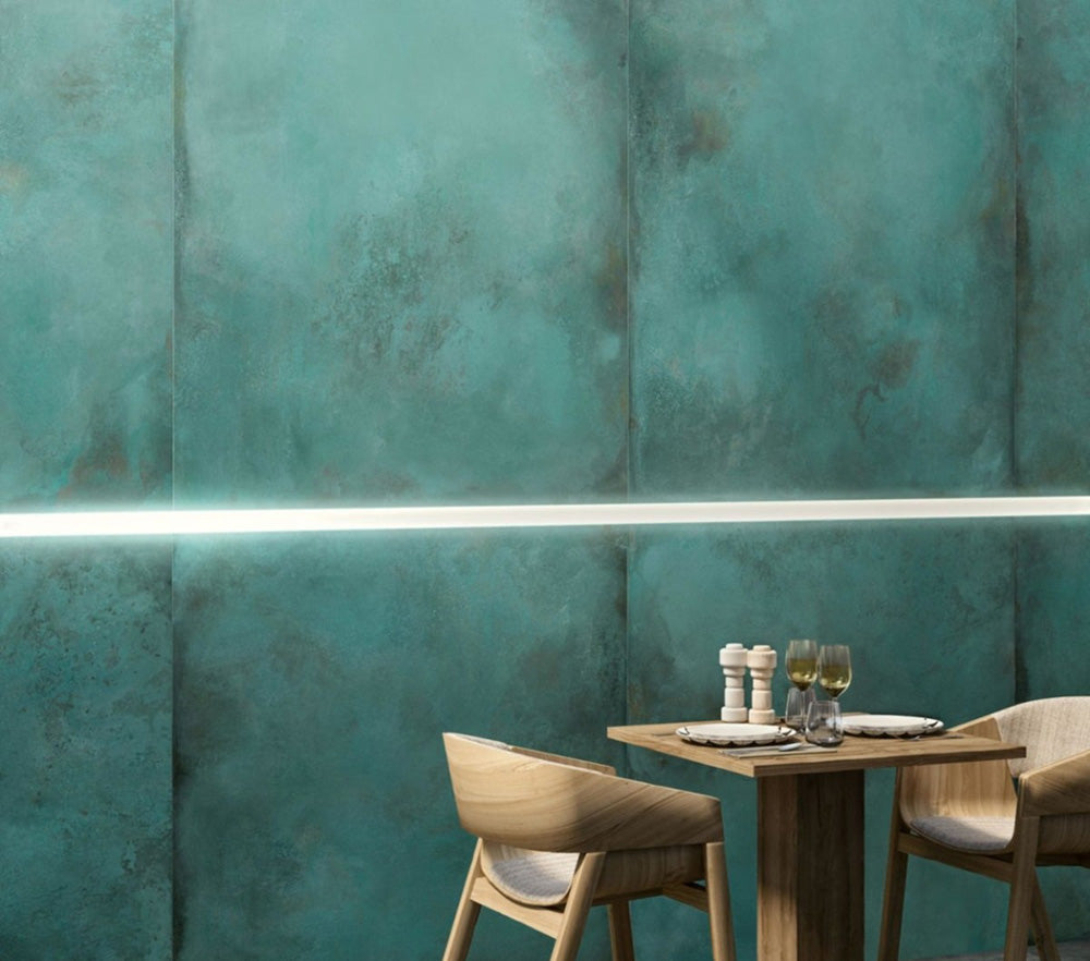 Contemporary dining area featuring Verde Copper Oxide 60cm x 60cm metallic effect wall tiles, paired with light wood furniture and subtle LED lighting to create a bold industrial-inspired feature wall.