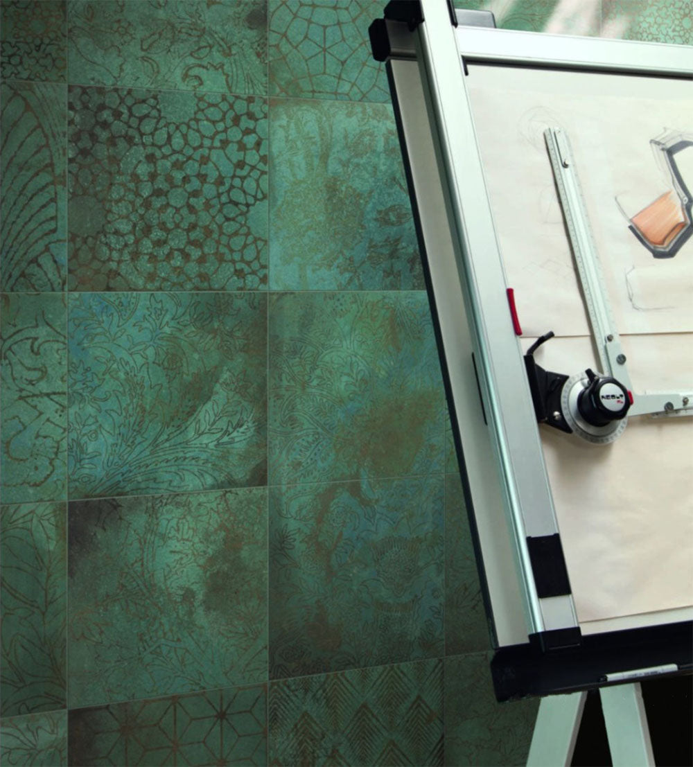 Contemporary workspace featuring Verde Patterns Copper Oxide 30cm x 30cm metallic effect porcelain wall tiles, showcasing decorative etched patterns in rich blue-green tones behind a modern drawing board.