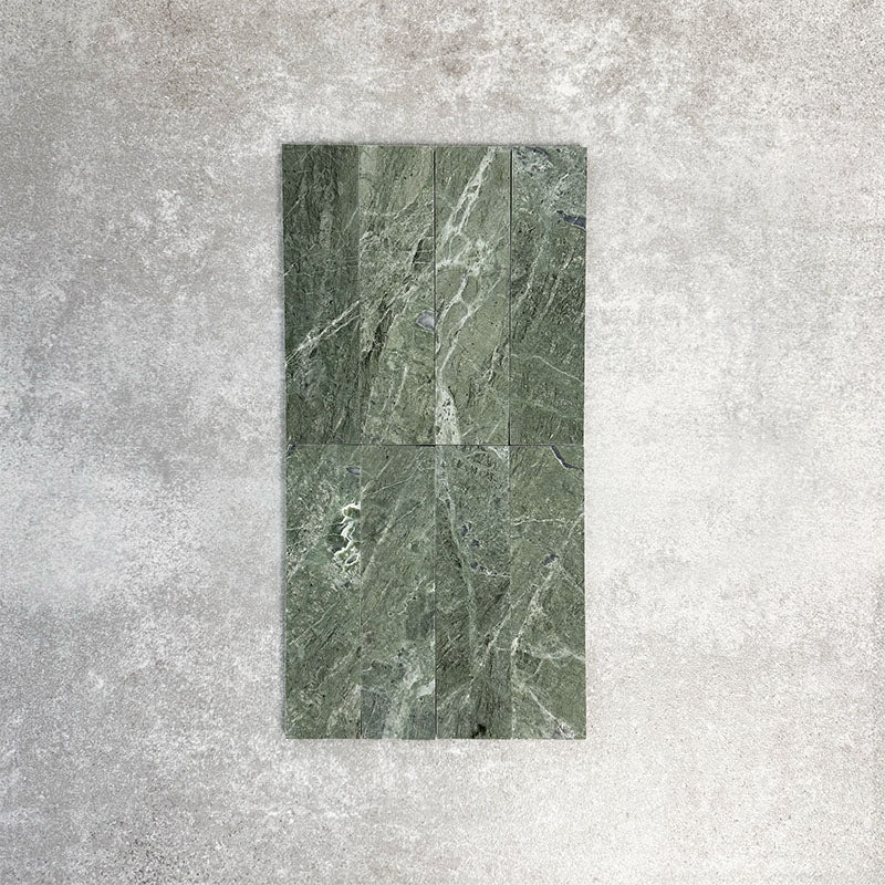 Fayrouz Verde 5x20cm natural marble tiles with a honed finish arranged vertically, showcasing rich green tones and natural veining, displayed against a neutral textured background in a clean product setting.