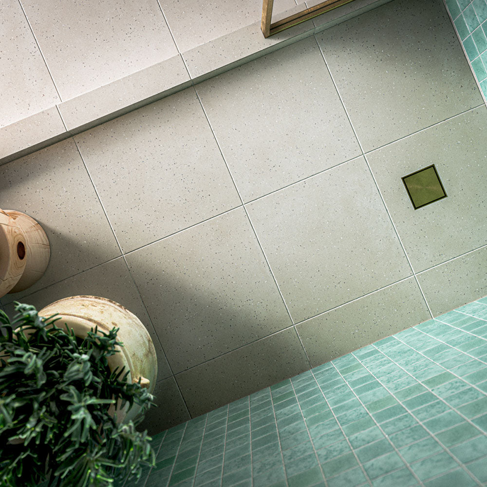 Contemporary walk-in shower featuring Verona Micro Sand 60cm x 60cm terrazzo effect porcelain wall tiles, paired with white floor tiles, brass shower fittings and an arched alcove for a Mediterranean-inspired bathroom.