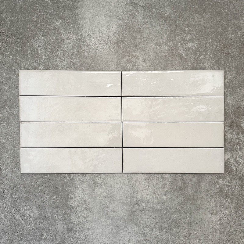 Nomad White brick wall tiles in a 6 × 24.6cm format, shown laid together to highlight the soft white colour, gloss finish and subtle surface variation.
