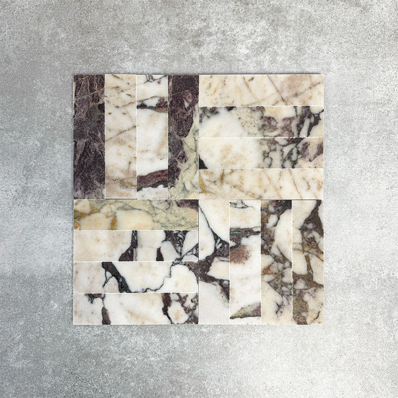 Arrangement featuring Fayrouz Viola 5x20cm natural marble tiles with a honed finish, laid in a basketweave pattern to create visual movement, showcasing a white base with bold burgundy and warm-toned veining and natural variation.