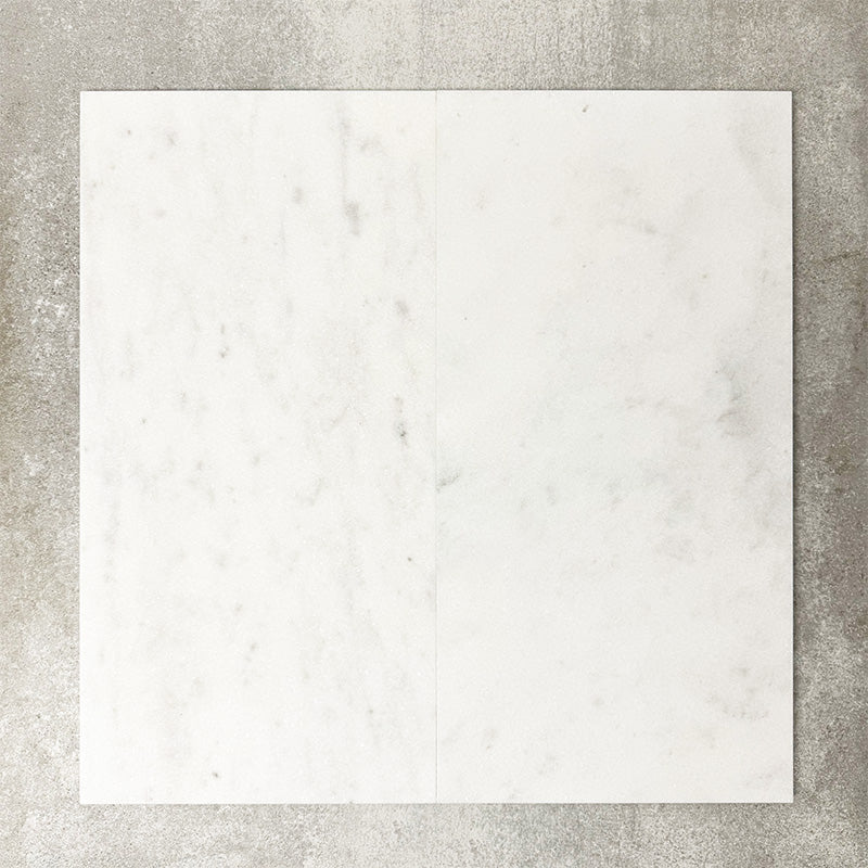 Close-up of Fayrouz White natural marble tiles in a honed finish, 30.5x61cm format, showcasing a soft white base with subtle grey veining and gentle tonal variation, creating a refined and timeless look for wall and floor applications.