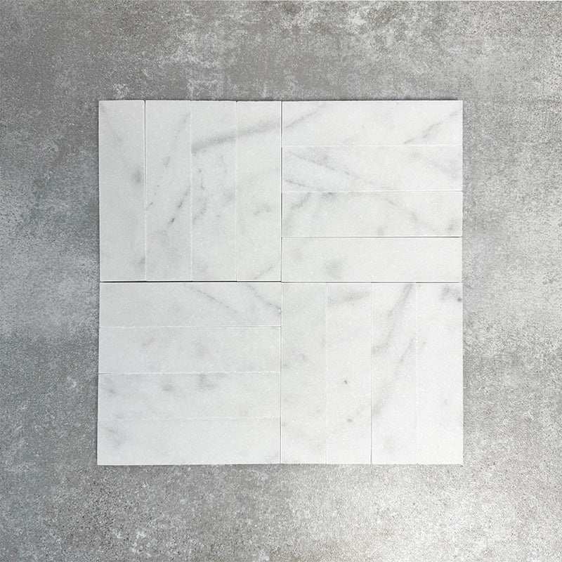 Arrangement featuring Fayrouz White 5x20cm natural marble tiles with a honed finish, laid in a basketweave pattern to create subtle movement, showcasing a soft white base with delicate grey veining and natural tonal variation.