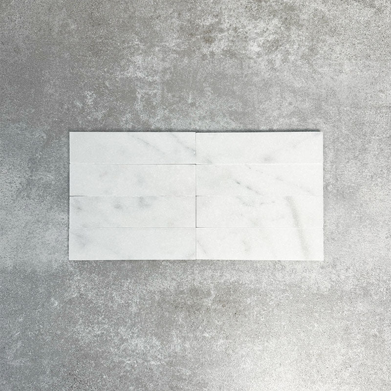 Fayrouz White 5x20cm natural marble tiles with a honed finish, featuring a soft white base with subtle grey veining, arranged in a neat grid to highlight natural variation and tonal consistency.