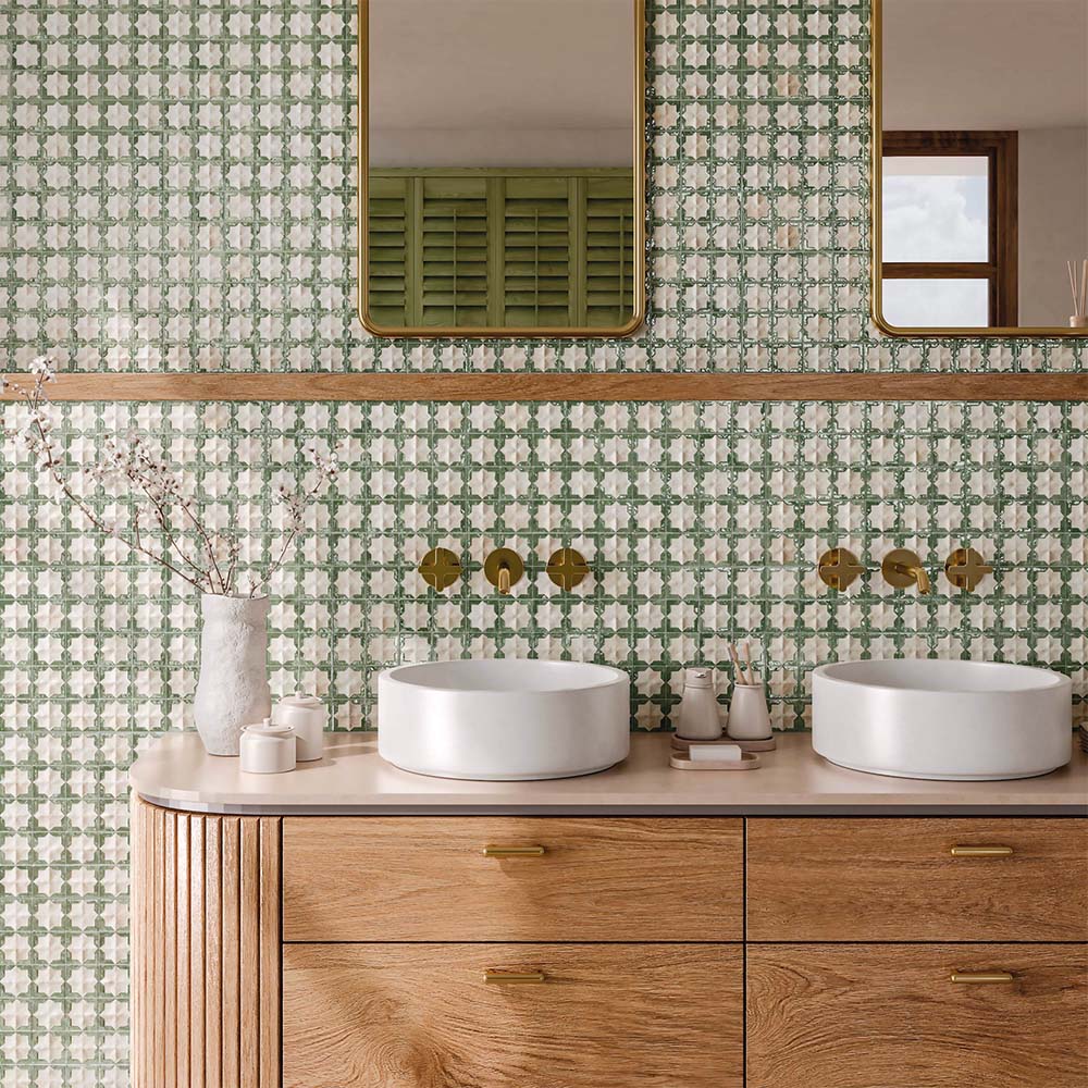 Bathroom vanity featuring Zanzibar Moroccan Emerald Green ceramic wall tiles in a repeating Moroccan style geometric pattern, paired with a light wood vanity, round white basins, brushed brass wall-mounted taps, timber shelving and contemporary mirrors for a warm Mediterranean-inspired bathroom.