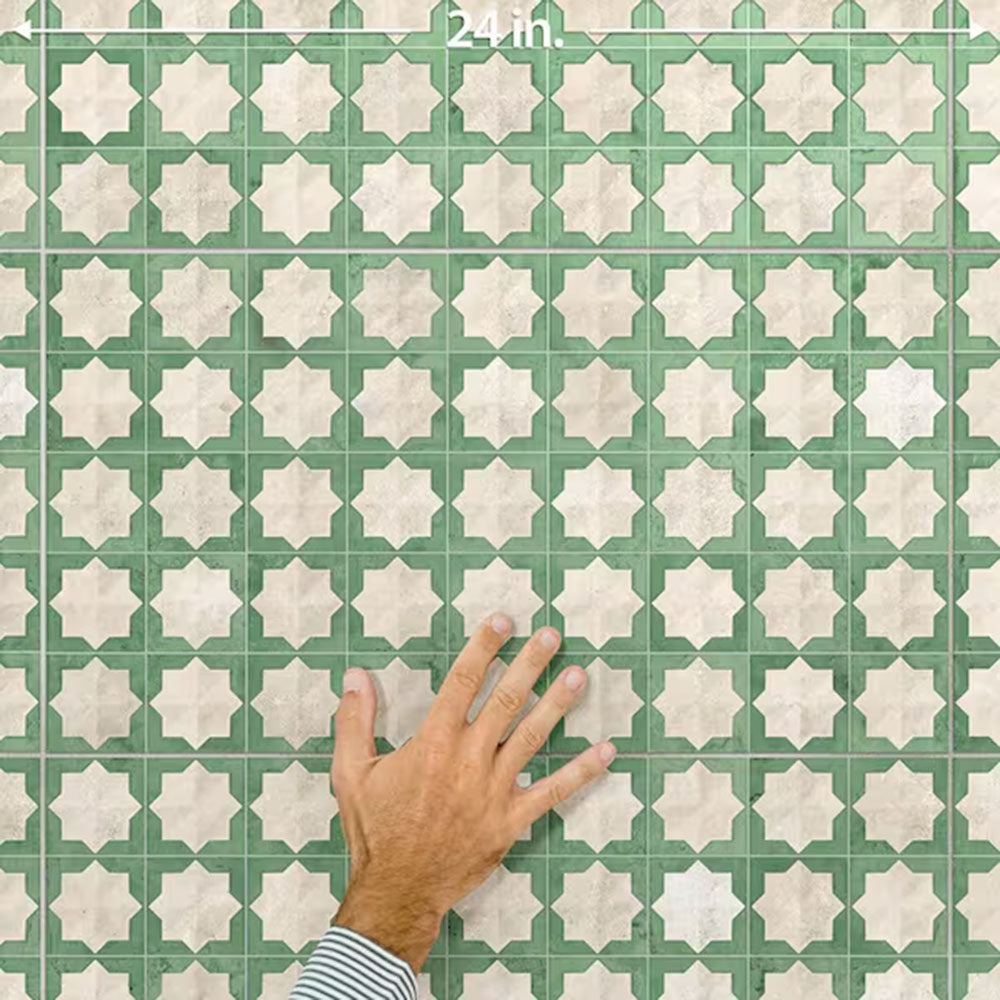 Close-up of Zanzibar Moroccan Emerald Green ceramic wall tiles in a repeating Moroccan style geometric star pattern, shown with a hand for scale to highlight the 31 x 56cm format, subtle tonal variation and textured glazed finish.