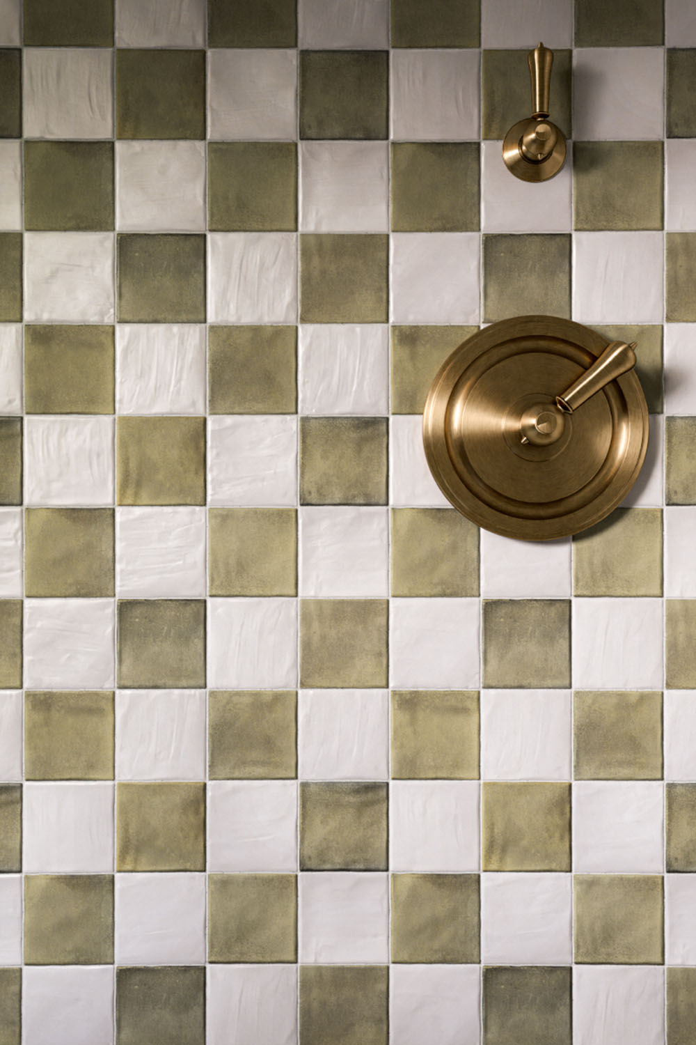 Zellige Oyster Square 10cm x 10cm Moroccan style tiles, showcasing their softly irregular surface and subtle tonal variation in a chequerboard layout, paired with aged brass shower fittings for a warm, characterful finish.